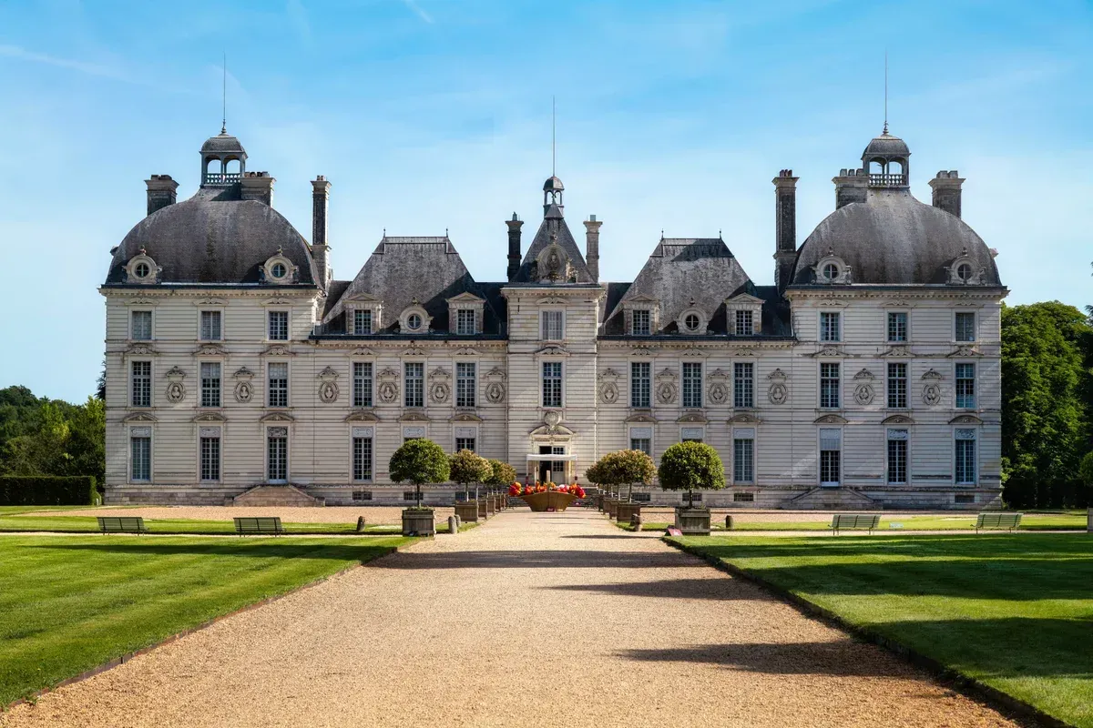 The symmetrical facade of Château de Cheverny under a blue sky, a château near the routes of Loire Valley wine and castle tours